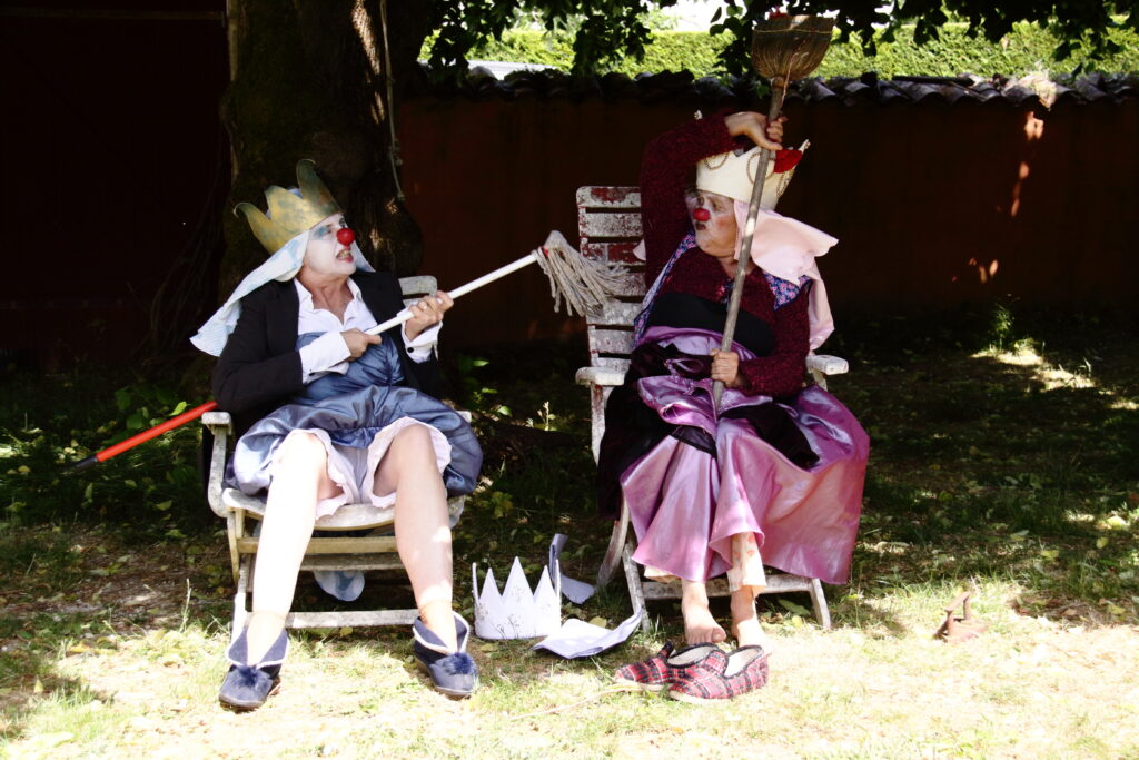 3 reines à la rue-2 Deux clownes se prennent pour des reines à l'ombre d'un arbre dans le spectacle 3 reines à la rue